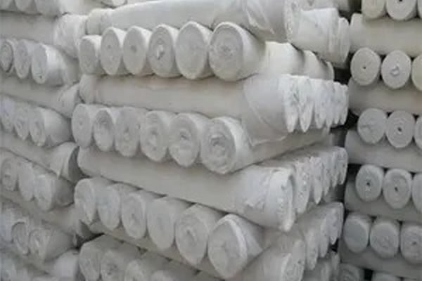 Stacks of white fabric rolls arranged in a warehouse or storage area.
